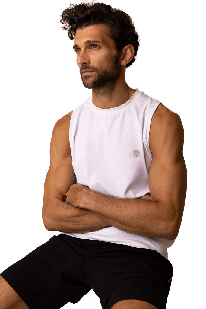 Image of male model sitting down with arms folded wearing the White Sahara Men's Gym Vest which is loose fitting and perfect for working out